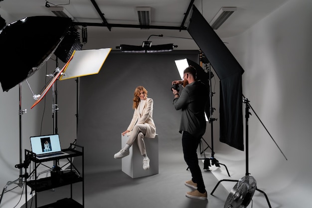 Model young woman preparing posing for photo taken with professional photographer in studio on