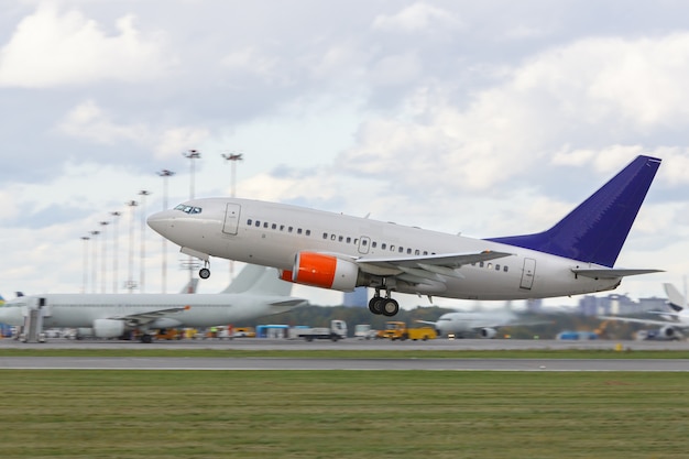 Modern airliner taking off from runway, airplanes on background, side view.