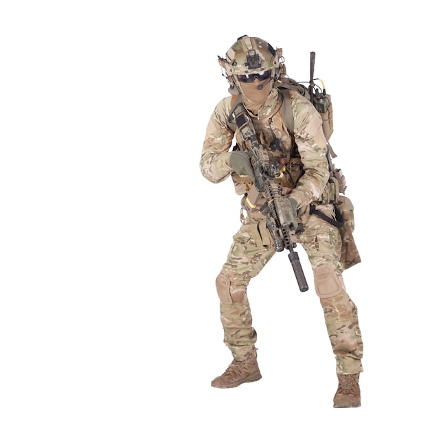 Modern army infantry rifleman in camo uniform, radio headset on helmet, ammo on load carrier, sneaking, crouching, aiming and shooting with service rifle studio shoot isolated on white background