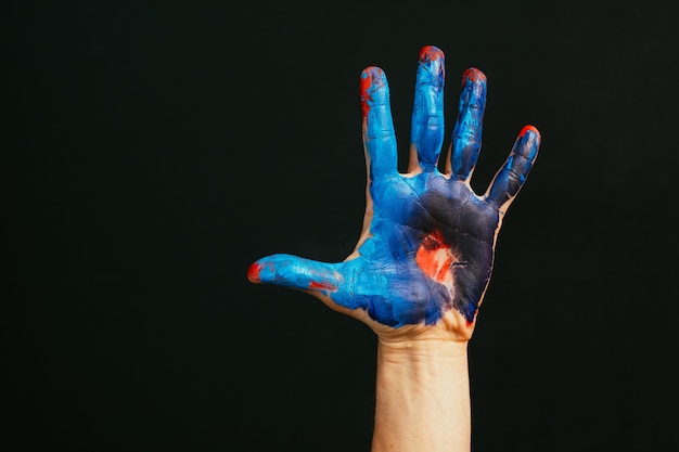 Modern art school. Master class. Creativity and inspiration. Closeup of male hand dirty with paint. Dark background empty space.