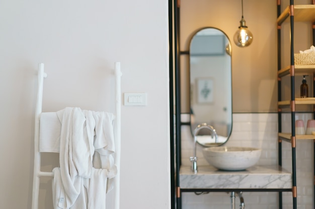 Modern bathroom, mirror with luminous lamps and sink, towel rack stairs.