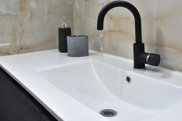 Modern bathroom sink minimalist design, white sink and slow running clean water from the faucet