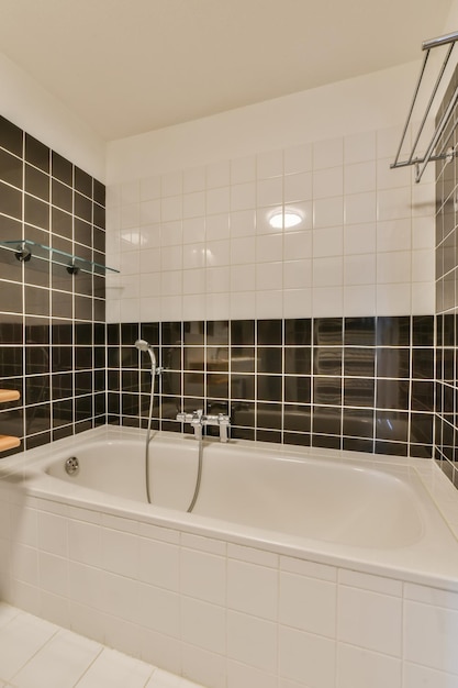 a modern bathroom with black and white tiles on the walls along with a large bathtub in the corner