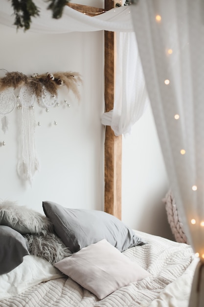 modern bedroom interior in scandinavian style with a cozy bed with wooden canopy and pillows