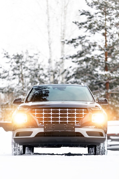 A modern black fourwheel drive SUV is parked on the side of a winter road Closeup of a car on a winter snowy road Family travel concept to a ski resort