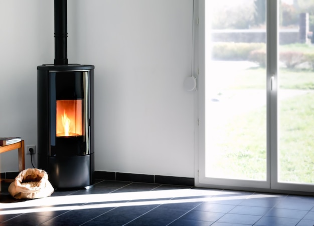 Modern black stove with burning flames and pellet bag in a living room