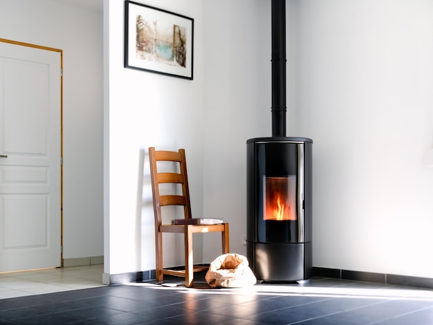 Modern black stove with burning flames and pellet bag in a living room