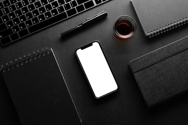 Modern black workspace compositions with keyboard notebook pen coffee and smartphone mockup