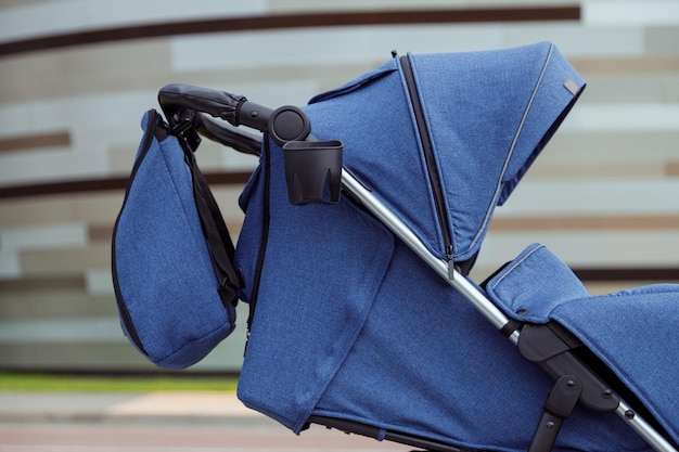 Modern blue baby stroller with hood and bag for parent outdoors side view