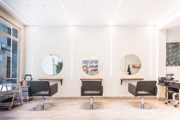 Modern bright beauty salon. Hair salon interior business with black chairs, round mirrors and neon lights.