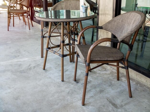 Photo modern brown chairs and round glass table near glass wall outside cafe