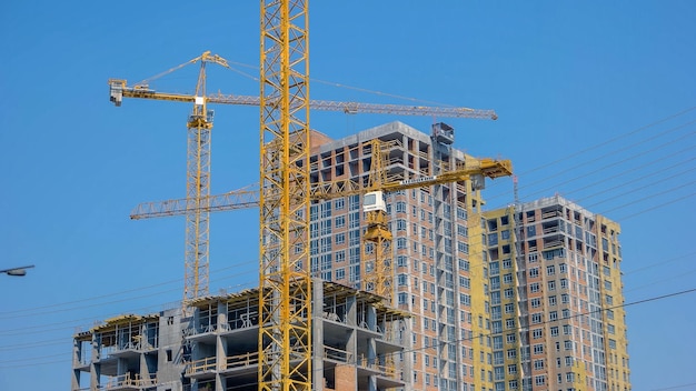 Modern building under construction against blue sky moving yellow crane