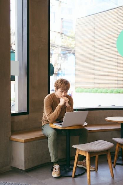 Modern business man connecting to wireless on his laptop computer during coffee break, male freelancer drink tea while working on notebook in loft studio, university student working at cafe or library