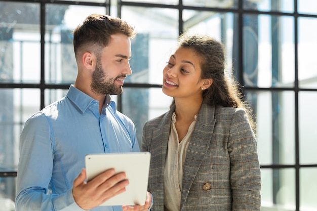 Modern business people are working using digital tablet and smiling while standing in the office