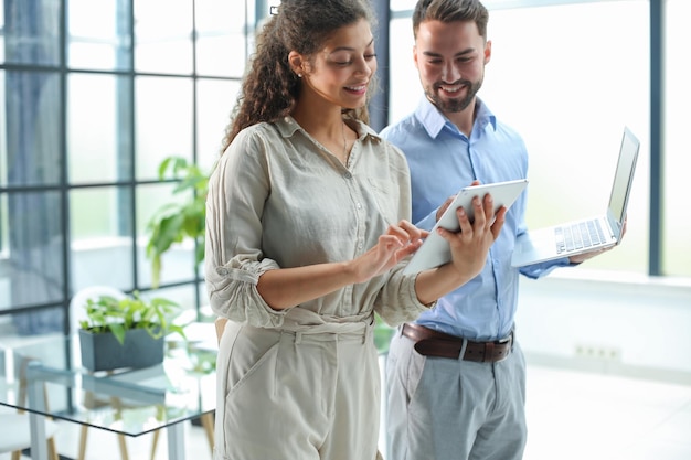 Modern business people are working using laptop and smiling while standing in the office