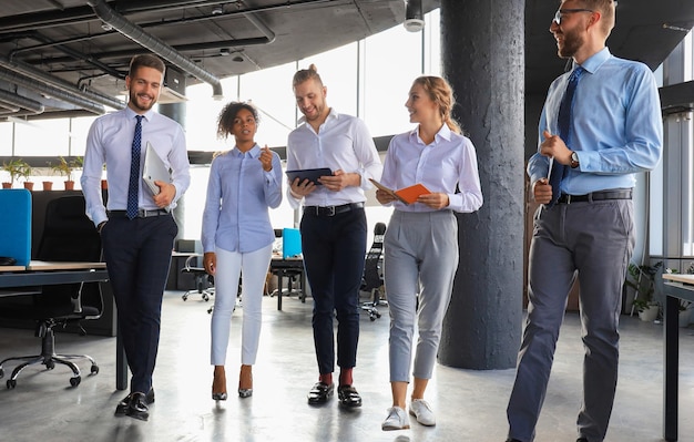 Modern business people discussing business and smiling while walking through the office corridor