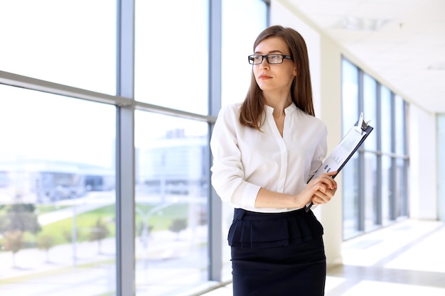 Modern business woman standing and keeping papers in the office with copy space area