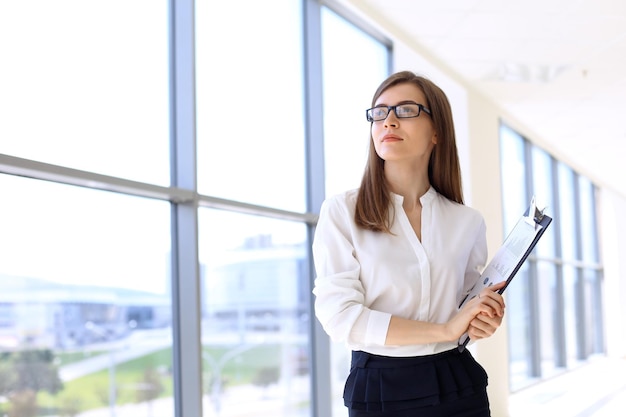 Modern business woman standing and keeping papers in the office with copy space area