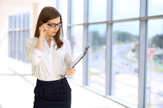 Modern business woman standing and keeping papers in the office with copy space area