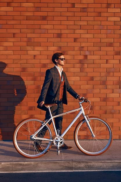 Modern businessman walking with bicycle on street