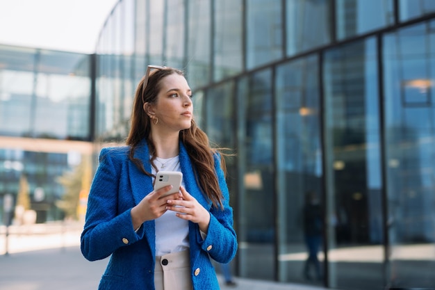 Modern businesswoman in blue suit using mobile phone copyspace high quality photo