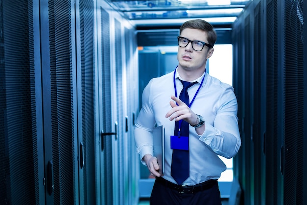 Modern cabinets. Determined professional operator holding a laptop and searching for the right server cabinet