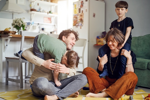 Modern caucasian happy family have fun and speding time with sons at home parents playing with kids