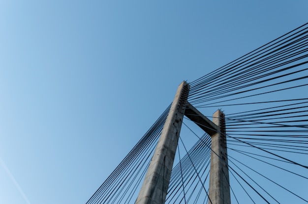 Modern cement bridge pylon structure over clear blue sky.