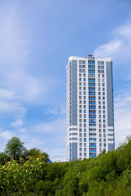 Modern cheap multi-storey apartment building on top of a hill against the sky