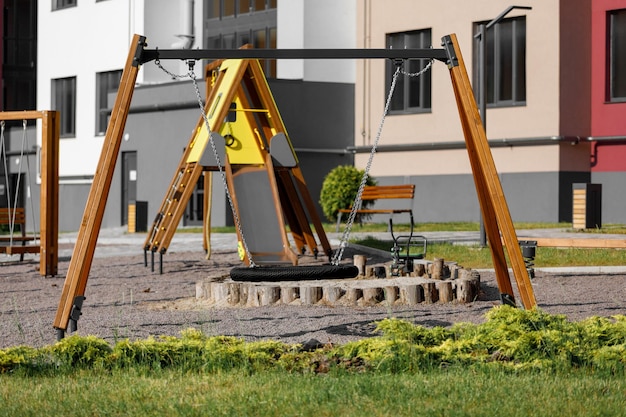 Modern children playground in courtyard of highrise residential buildings in sunny summer day