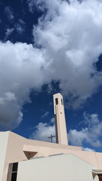 A modern church with white walls and a tall tower against a blue sky