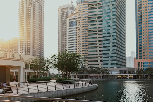 Modern city skyscrapers buildings at sunset time with business and residential towers around a lake