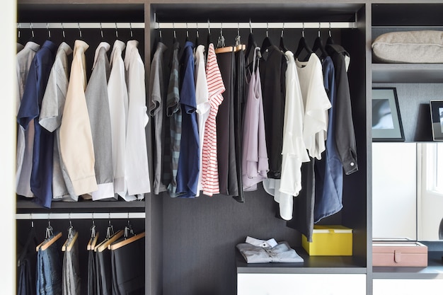 Modern closet with row of cloths hanging in black wardrobe