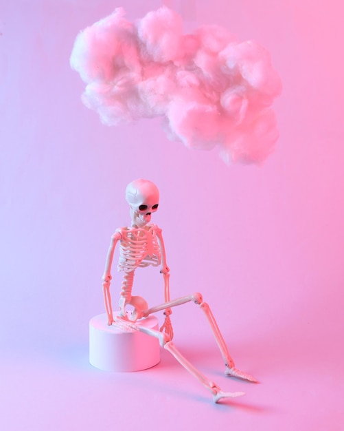 Modern composition of skeleton and floating fluffy cloud in blue pink neon gradient light Creative idea Halloween Concept Minimalism Surrealism