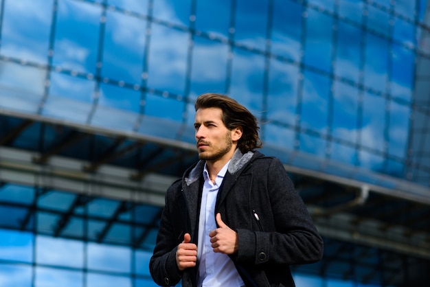 Modern confident young businessman in full suit standing outdoors