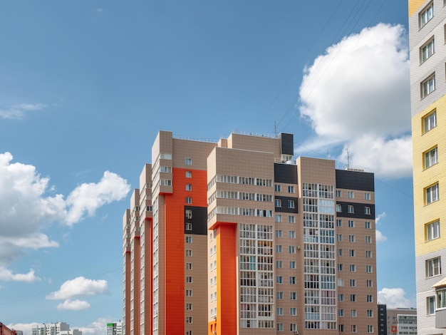 Modern construction, new neighborhood. Beautiful new buildings. Colored wall on the background of blue cloudy sky. Copy space.