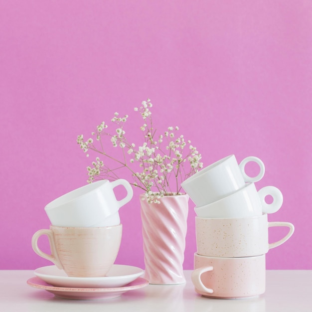 Modern cups on white table on background pink wall