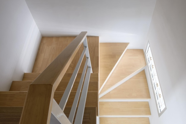 The modern curved wooden staircase with the white metal handrail in the urban house