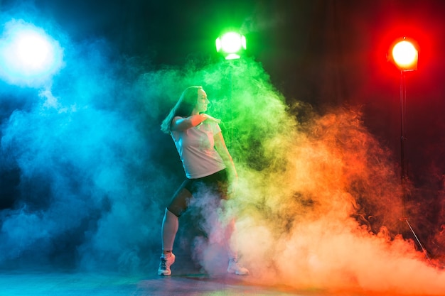 Modern dance concept - Cheerleading young woman dancing on coloured background.