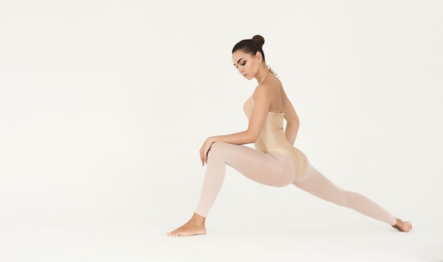 Modern dancer girl warming up before dancing, stretching legs on white background, copy space