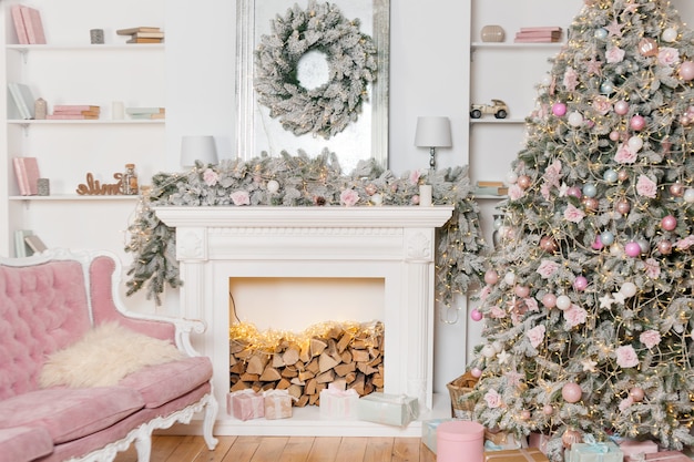 Modern design of the room with fireplace in light colors decorated with Christmas tree and decorative elements, New Year decorations, Happy Winter Holidays, Christmas tree and presents.