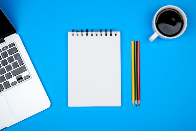 Modern designer office desk table with blank notebook page laptop computer and cup of coffee