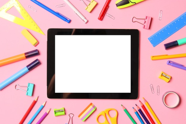 Modern digital tablet and school stationery on a colored background top view