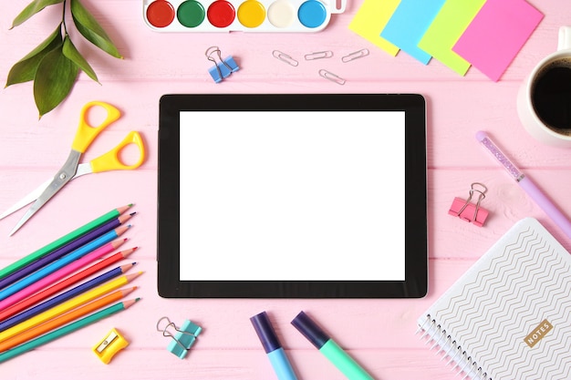 Modern digital tablet and school stationery on a colored background top view