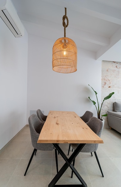 Modern dinning room space with a handcrafted table, four chairs and a hanging lamp above in a house