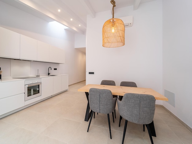 Modern dinning room space with a handcrafted table, four chairs and a hanging lamp above in a house