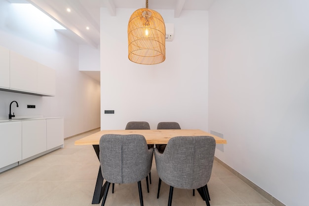 Modern dinning room space with a handcrafted table, four chairs and a hanging lamp above in a house