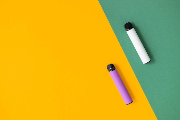 Modern disposable electronic cigarettes on color background