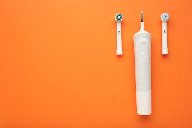 Modern electric toothbrush on orange background Controlled tool for daily oral care