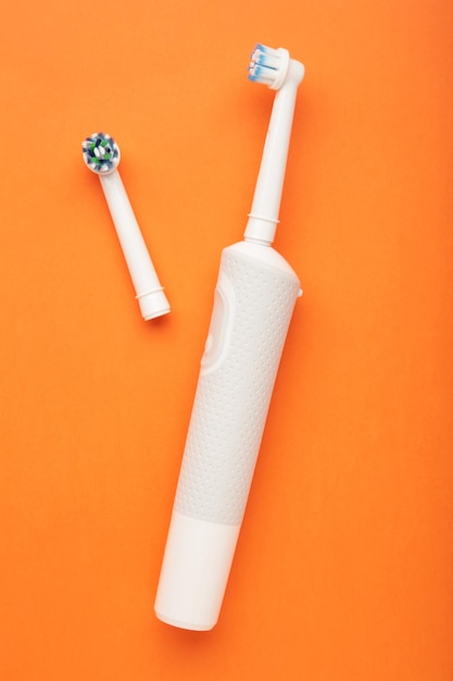 Modern electric toothbrush on orange background Controlled tool for daily oral care